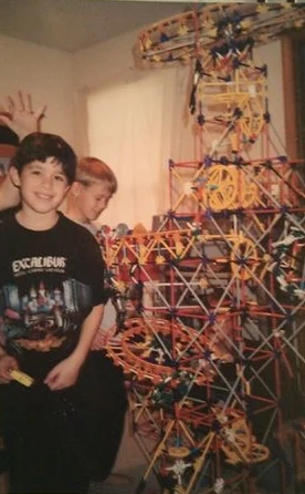 9-year-old Mark standing next to a K'NEX tower that reaches the ceiling