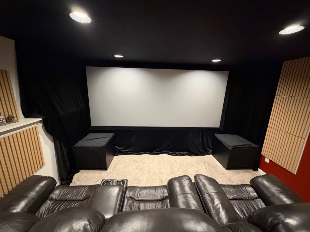 Custom home theater front stage view with 135-inch screen, acoustic panels, and dual subwoofers