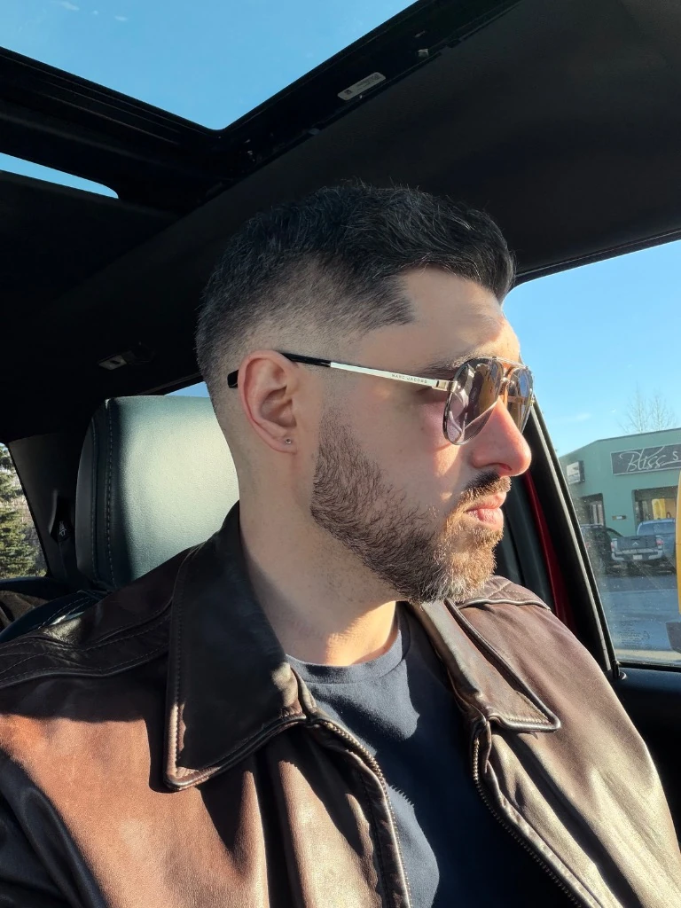 Mark in golden hour light wearing aviator sunglasses beside a truck
